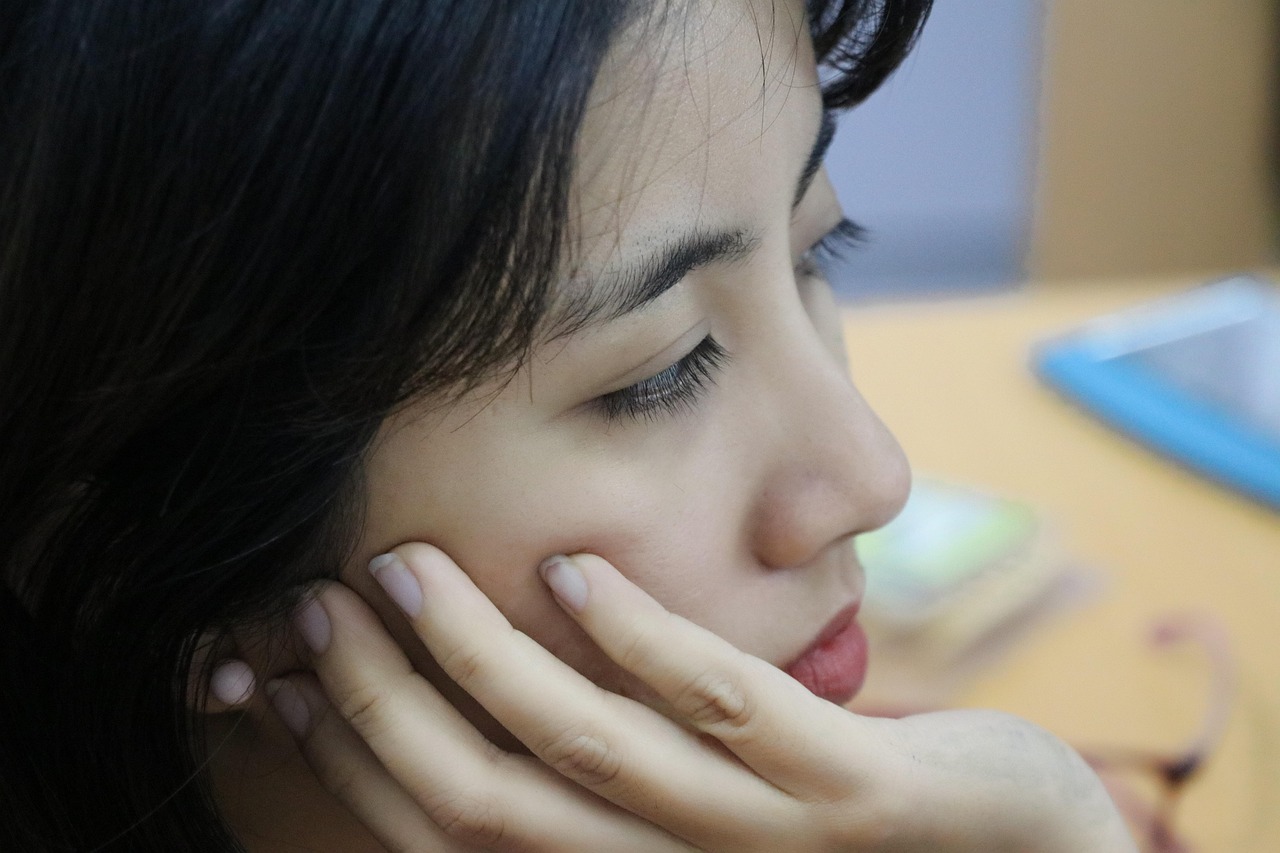 Woman with hand on cheek thinking at a desk